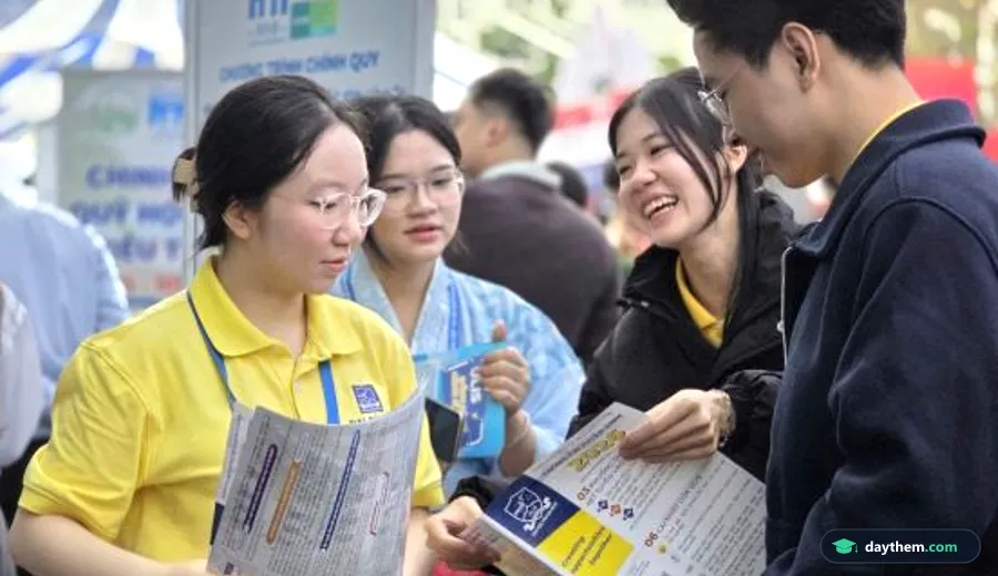 Giảng viên tư vấn tuyển sinh đại học cho học sinh phổ thông tại bàn tư vấn có backdrop của trường