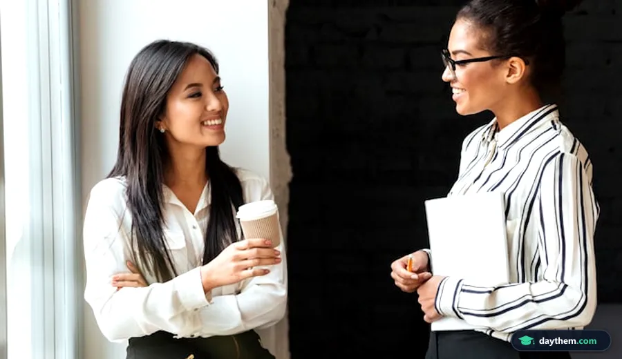 Hai nữ nhân viên công sở ngồi đối diện, trò chuyện và giao tiếp bằng cử chỉ tay trong cuộc trao đổi trực tiếp