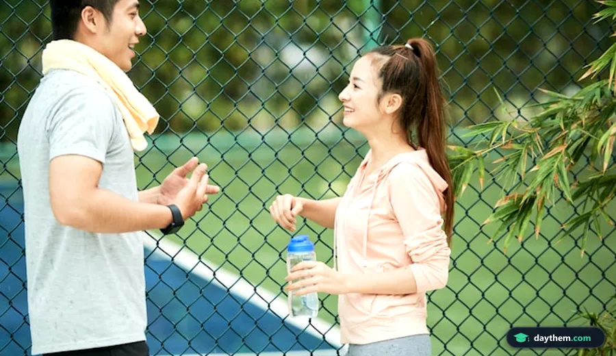 Đôi nam nữ mặc đồ thể thao đứng trò chuyện ngoài trời, minh họa cho tình huống giao tiếp tiếng Anh về thể thao.