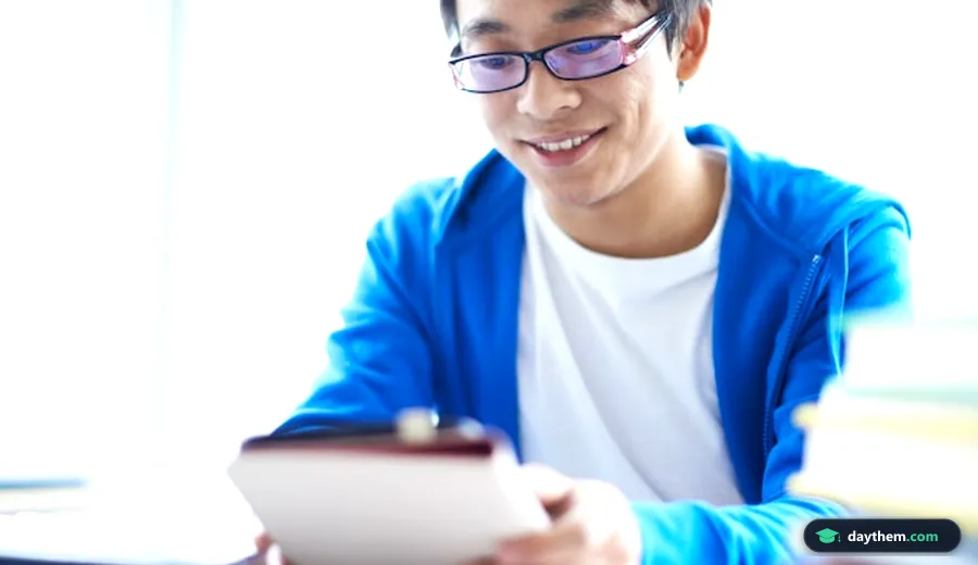 Nam sinh ngồi tại bàn học, mỉm cười nhìn vào máy tính bảng khi tìm hiểu thông tin tuyển sinh ngành Quản lý giáo dục.