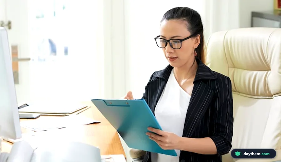 Kế toán trường học kiểm tra số liệu và tài liệu tài chính với máy tính trên bàn làm việc