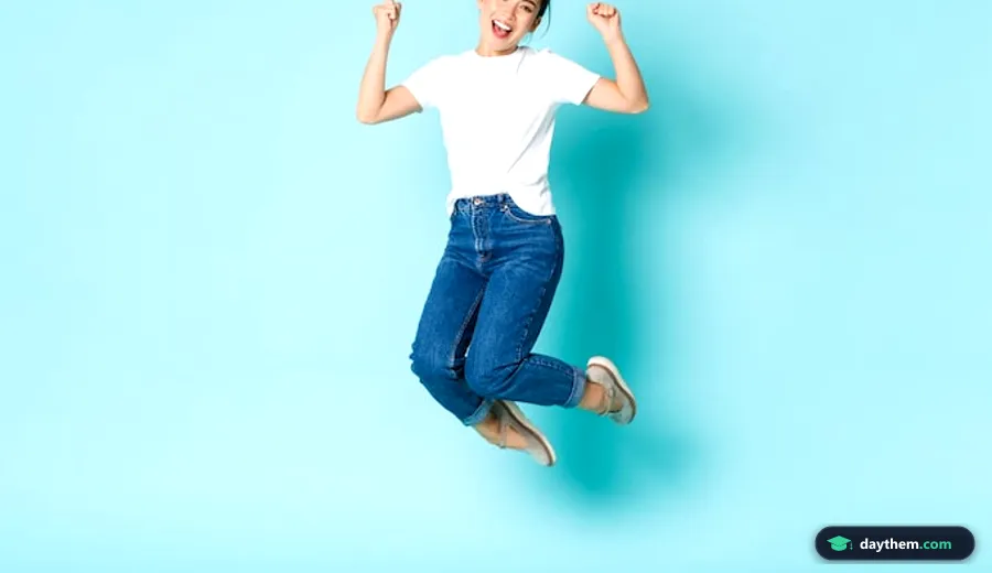 Cô gái trẻ người châu Á nhảy cẫng lên vui sướng, cười tươi trên nền tường xanh dương nhạt trong bài học tiếng Anh về diễn tả cảm xúc